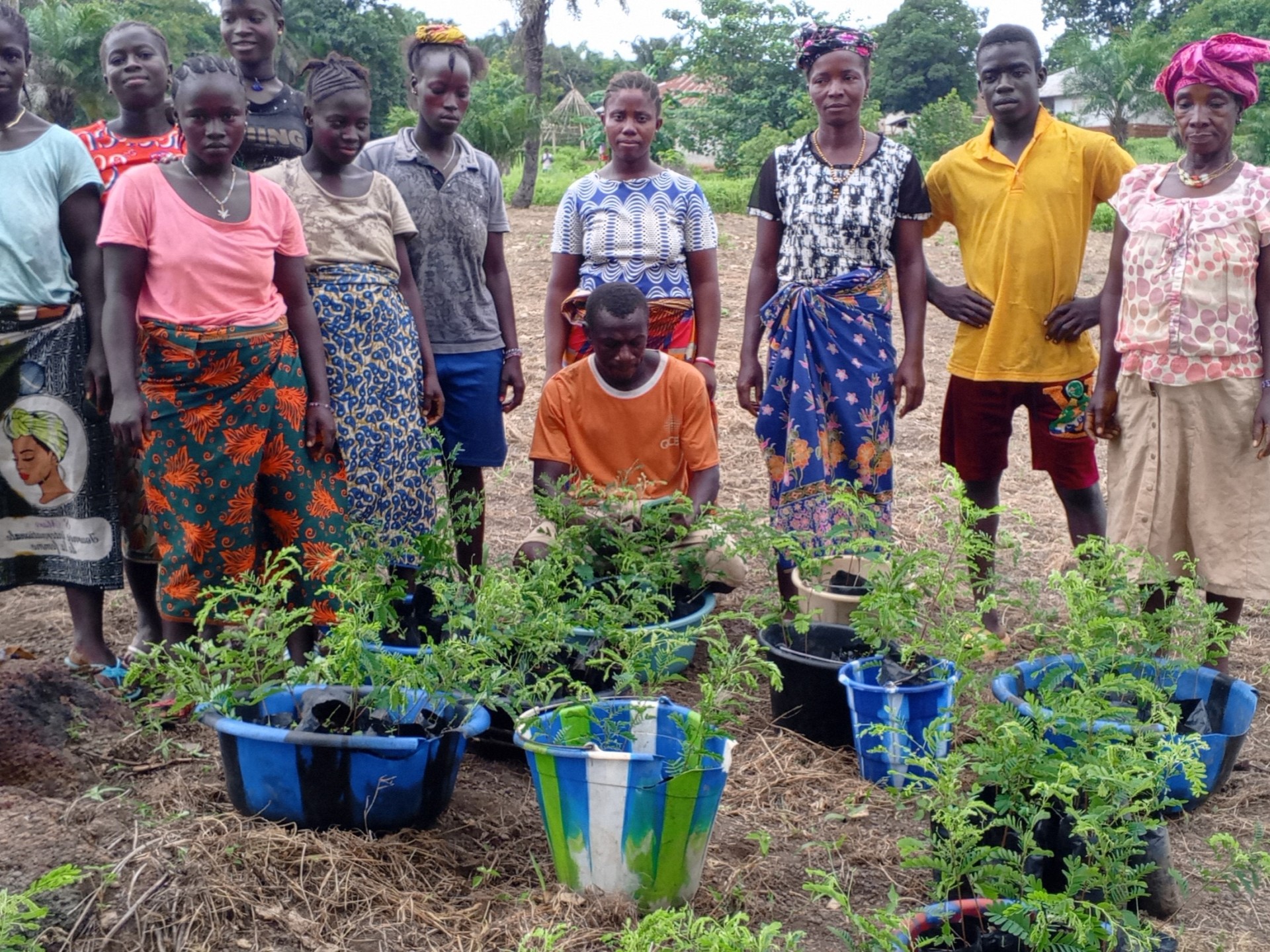 Stolze Bewohner des Impact Villages zeigen die neuen Pflanzen, die sie einpflanzen werden.