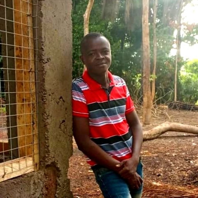 Ein junger afrikanischer Mann steht neben einem Haus