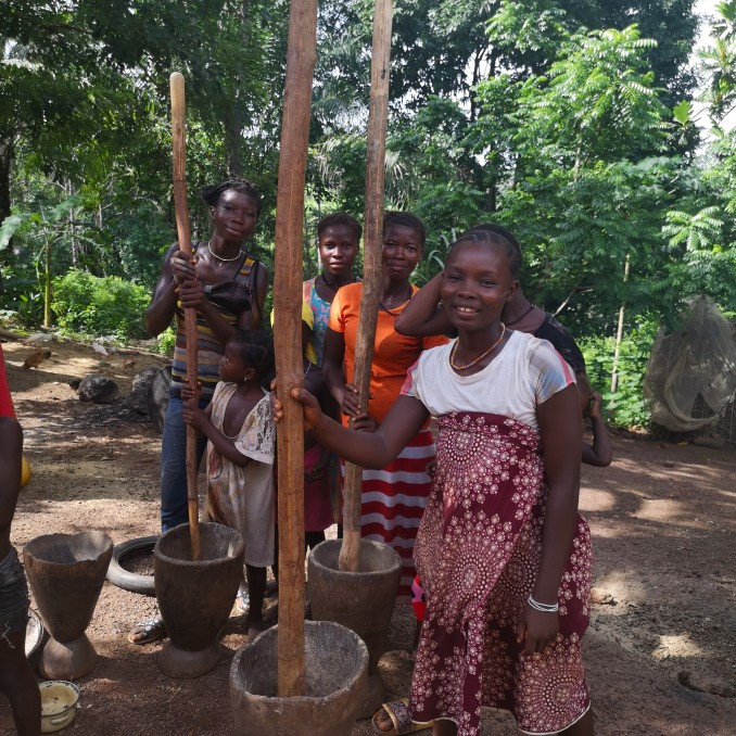 Afrikanerinnen im Impact Village bei der manuellen Verarbeitung von Lebensmitteln