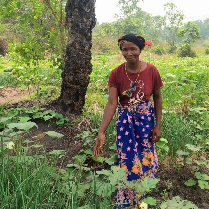 Afrikanische Frau mit einem farbenfrohen Rock steht in einem Feld