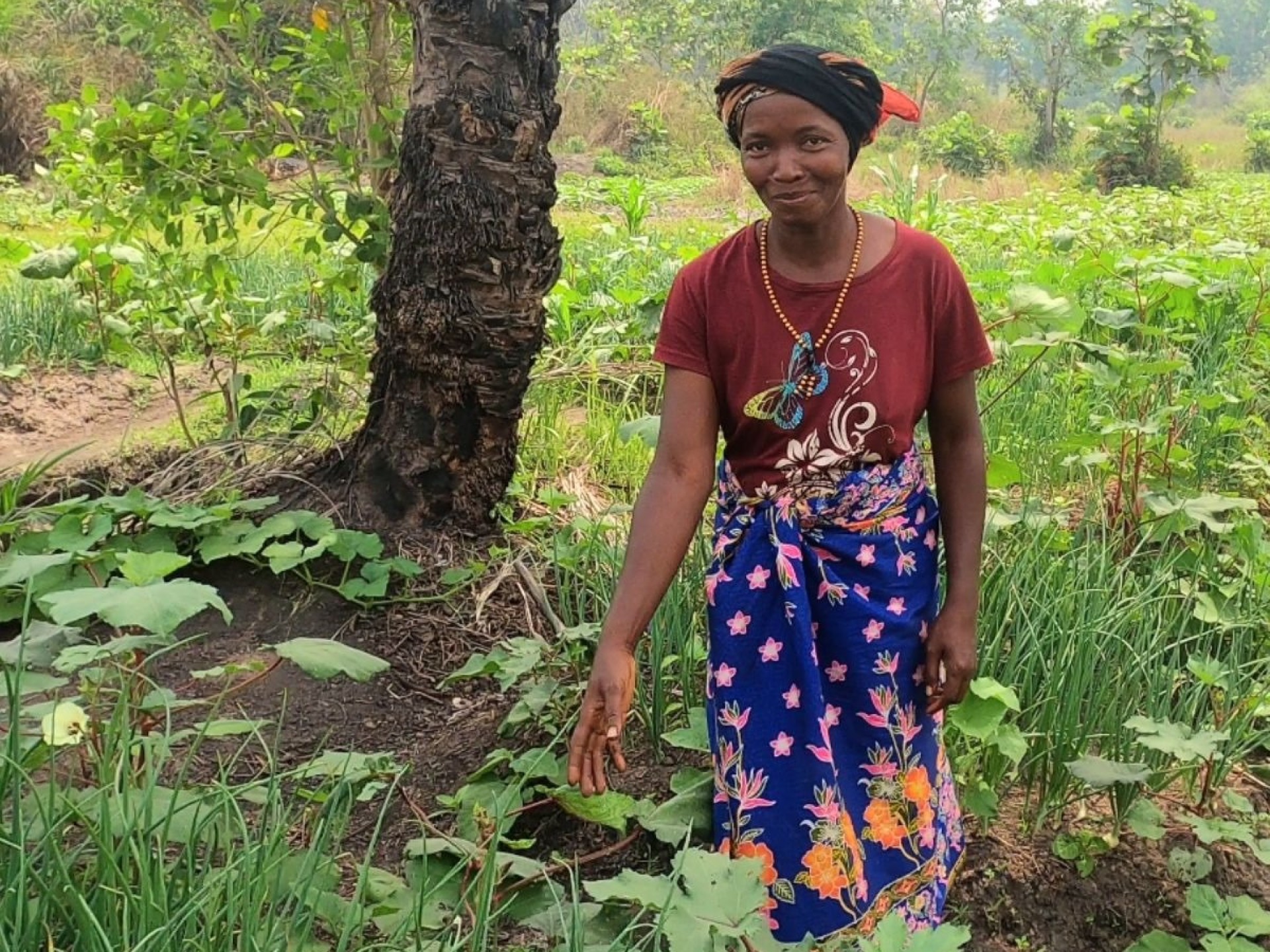 Afrikanische Frau mit einem farbenfrohen Rock steht in einem Feld