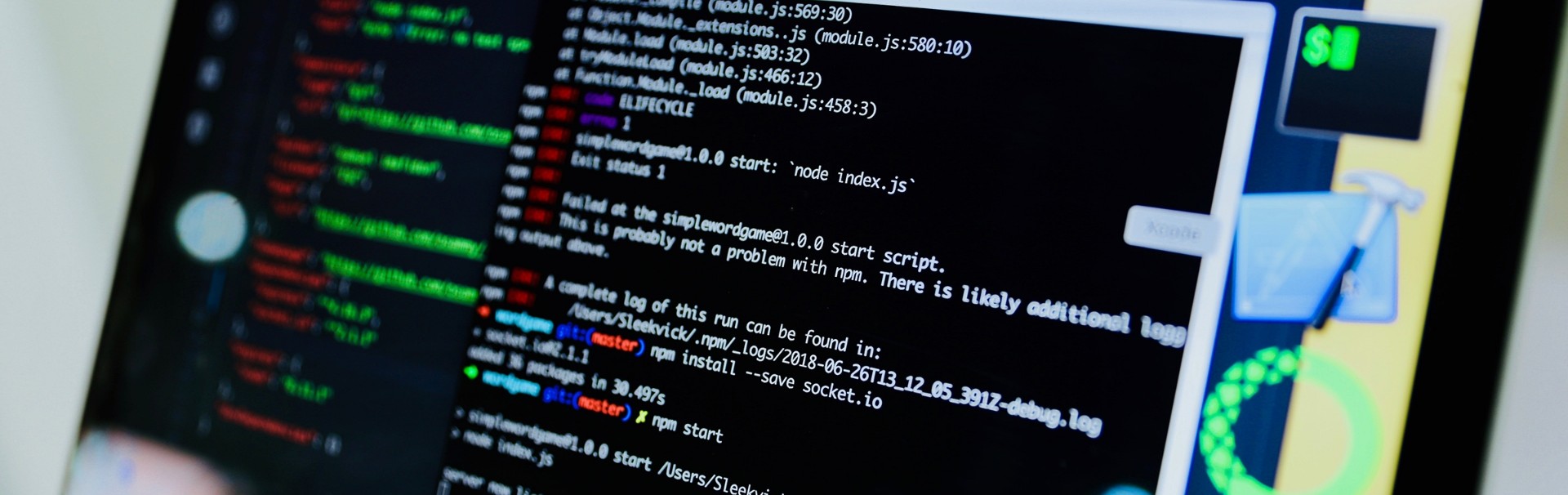 Blick von schräg rechts auf einen Computerbildschirm. In einem Fenster ist Programmcode in weißer Schrift auf schwarzem Hintergrund zu sehen. Manche Code-Elemente sind durch unterschiedliche Schriftfarben hervorgehoben.