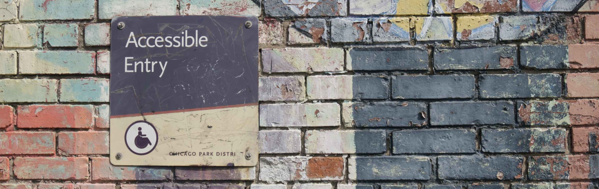 Auf einer bunt bemalten Mauer ist ein schwarz-gelbes Schild mit der Aufschrift 