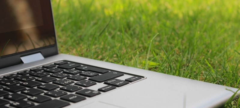 Ein aufgeklappter Laptop liegt im Gras.