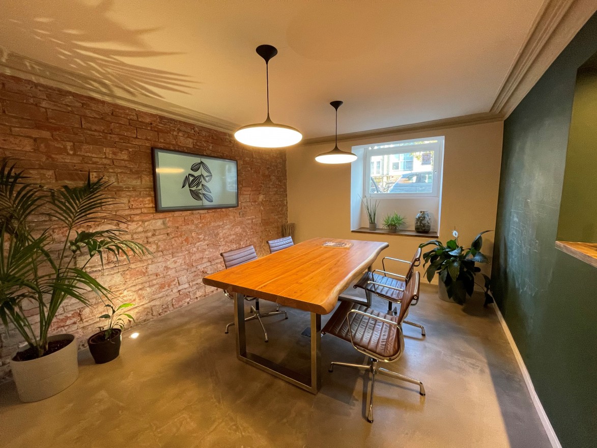 Besprechungsraum mit Besprechungstisch und vier Stühlen, sowie einem Smart-TV für Präsentationen