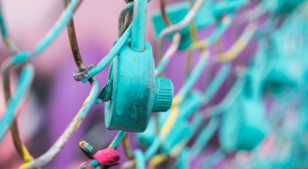 Ein Vorhängeschloss hängt an einem Maschendrahtzaun