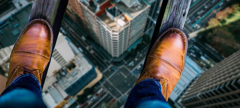 Füße stehen auf zwei Holzbalken in hoher Höhe