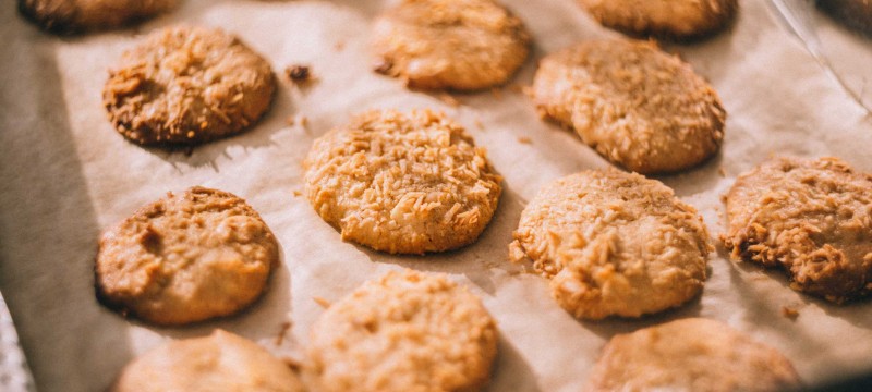 Hellbraune Kekse liegen nebeneinander in einer flachen Blechdose.