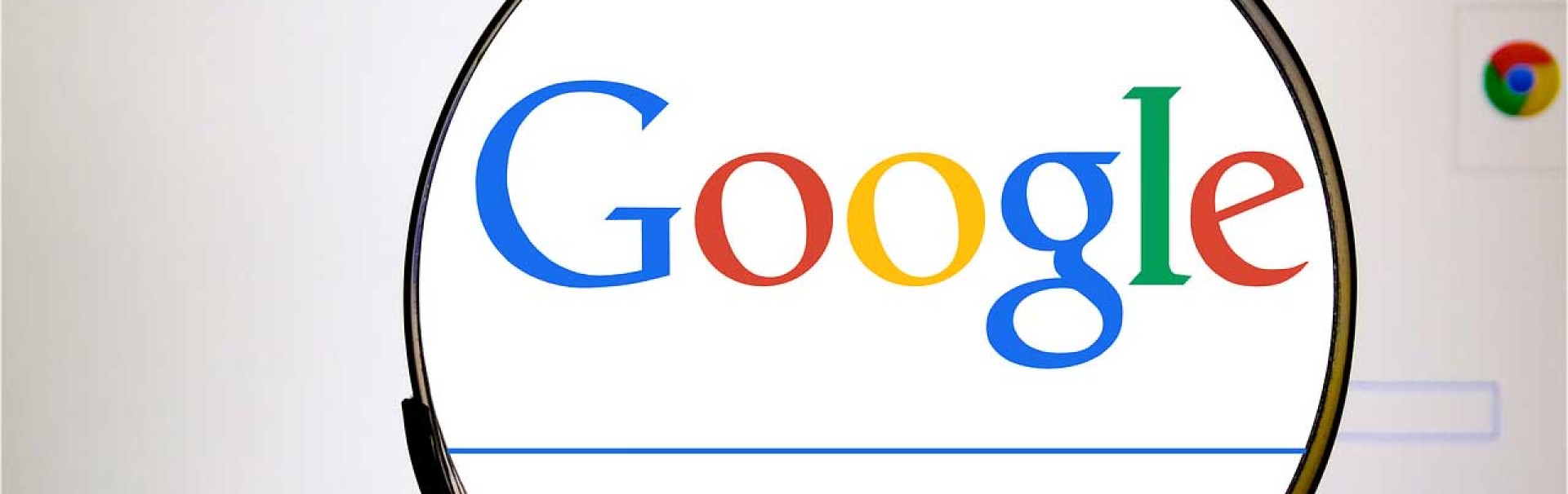 Durch eine Lupe wird der Schriftzug von Google und das Eingabefeld der Suchmaschine vergrößert sichtbar.