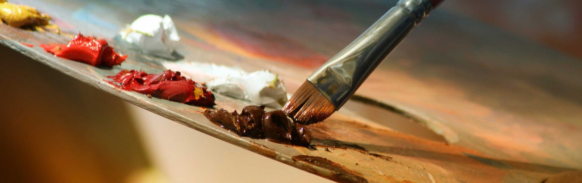 Auf einer Malerpalette sind mehrere Kleckse mit Farbe, und ein Pinsel wird in einen Farbklecks getunkt.