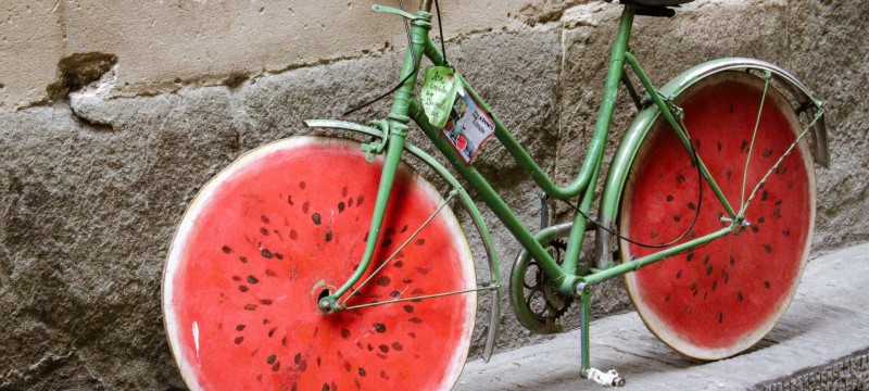 Ein grünes Fahrrad lehnt an einer Wand. Die Räder sehen aus wie eine angeschnittene Wassermelone.