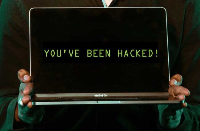 zwei Hände halten einen aufgeklappten Laptop, auf dem Bildschirm steht: You've been hacked.